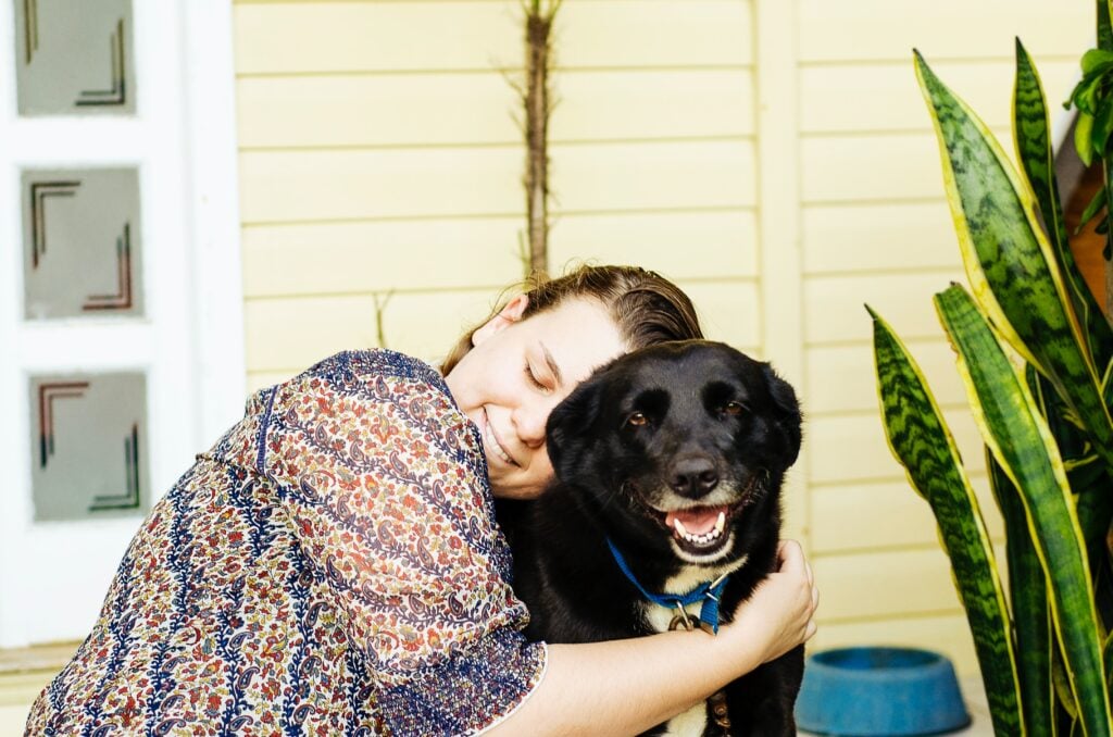 woman hugging her dog while smiling