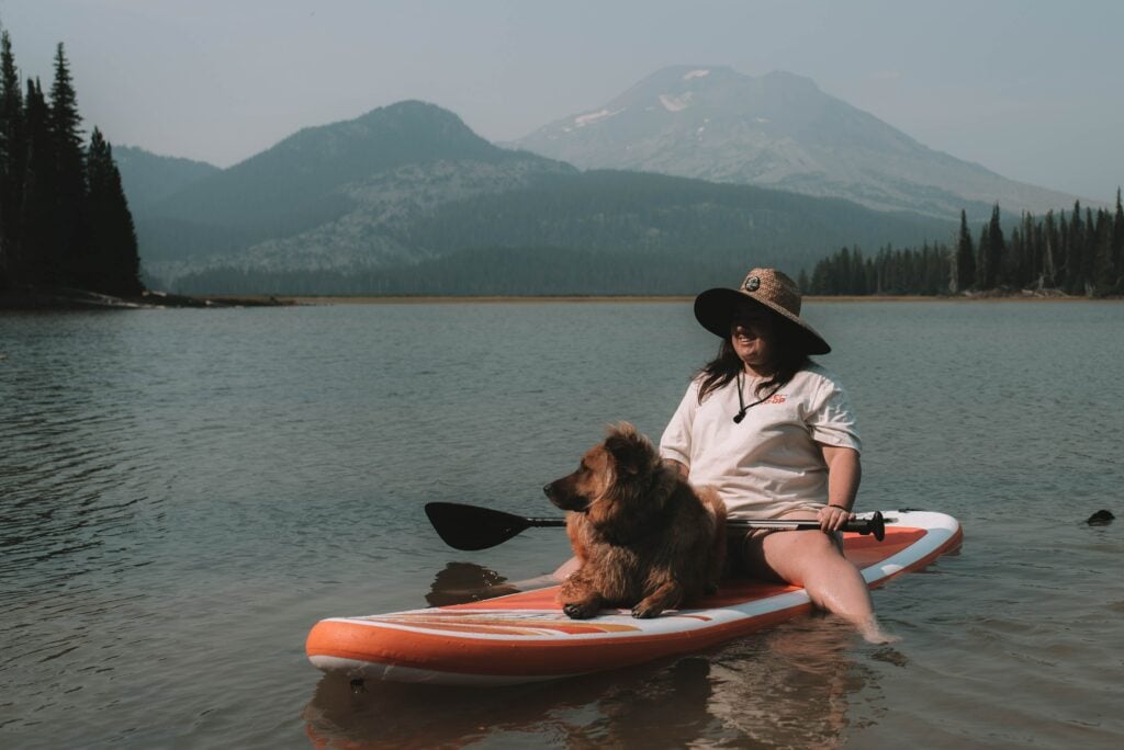 dog and human sitting on a kayak in a lake with beautiful background